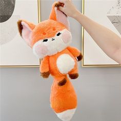 a person holding up a stuffed animal that looks like a fox