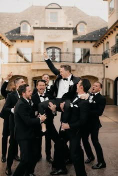 a group of men in tuxedos standing around each other