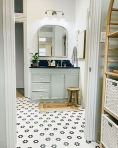 a bathroom with a sink, mirror and stool next to a doorway that leads into another room