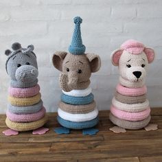 three crocheted stuffed animals sitting next to each other on top of a wooden table