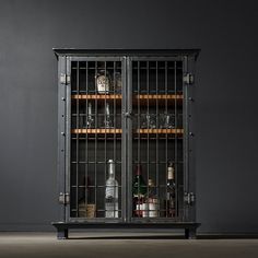 an old metal cabinet with wine bottles and glasses in it, against a dark wall