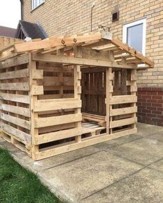 a building made out of wooden pallets in front of a brick wall and grass