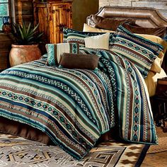 a bed covered in a blue and brown comforter next to a wooden headboard