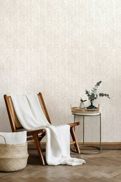 a chair and table in front of a wall with a plant on the floor next to it