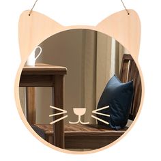 a cat's face is seen through a circular hole in the wall next to a chair