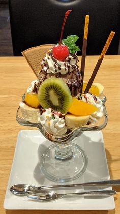 an ice cream sundae with kiwi, oranges and cherries on top