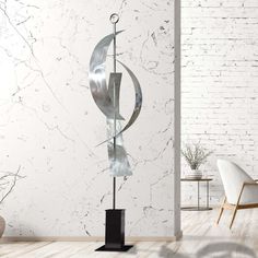 a metal sculpture sitting on top of a wooden floor next to a white brick wall