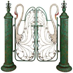 an ornate iron gate with two peacocks on it's sides and one bird sitting on top