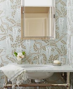 a white sink sitting under a bathroom mirror next to a wall mounted faucet