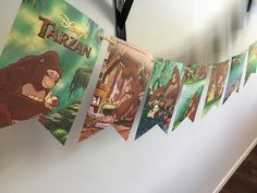 there are many pictures hanging on the wall with clothes pins in front of them that say disney's tarzan