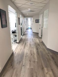 an empty hallway with white walls and wood flooring is pictured in this image from the inside