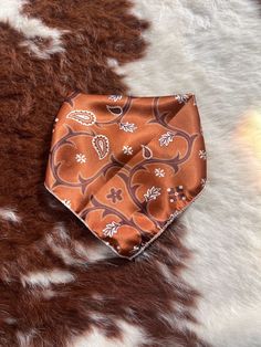 an orange and brown tie laying on top of a cowhide rug