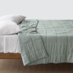 an unmade bed with two pillows on top of it and a green comforter