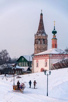 a horse drawn sleigh in front of a church on a snow covered hill