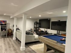 a living room filled with furniture and a pool table in front of a flat screen tv