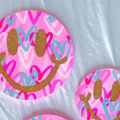 three pink and blue paper plates with gold glitter hearts on them are sitting on a white sheet