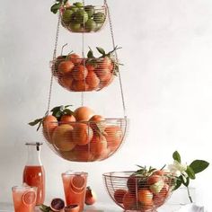 three tiered baskets filled with oranges and strawberries on a white countertop