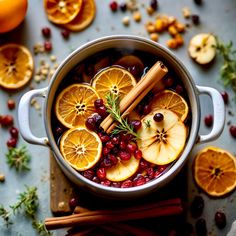 a pot filled with oranges, cranberries and cinnamon on top of a table