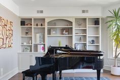 a living room with a black piano in the center and shelves filled with bookshelves