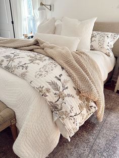 a bed with white comforter and pillows on top of it in a bedroom next to a window