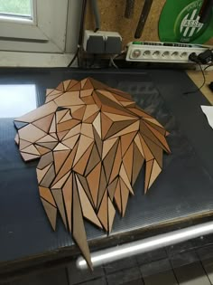 an animal made out of wood sitting on top of a metal counter next to a window