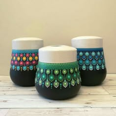 three black and white vases with colorful designs on them