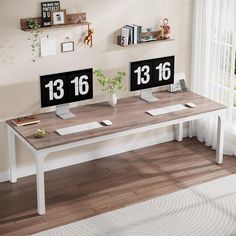 two computer monitors sitting on top of a wooden desk in front of a white wall