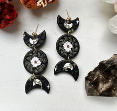 two pairs of black and white earrings sitting on top of a rock next to some rocks