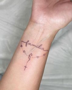 a person's wrist with a tattoo that says family and hearts on the cross