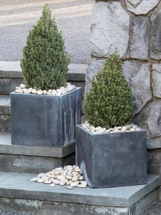 two cement planters sitting next to each other on concrete steps with rocks and plants in them