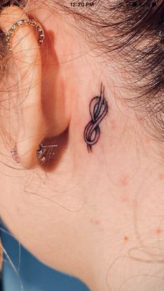 a woman's ear with a musical note tattoo on it