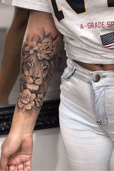 a woman's arm with a lion and flowers tattoo on her left arm, next to a mirror