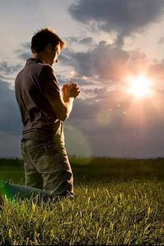 a man kneeling down in the grass praying