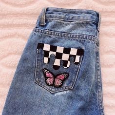 a pair of blue jeans with pink and black butterfly patches on the back of them