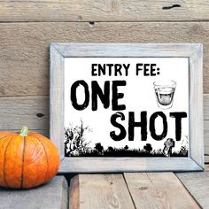 a sign that says entry fee one shot next to an orange pumpkin on a wooden table