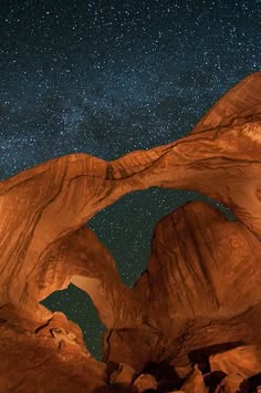 the stars are shining in the night sky above some large rocks and rock formations that look like archs