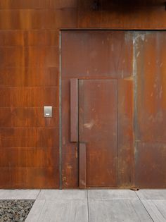 an open door on the side of a building with rocks and gravel in front of it