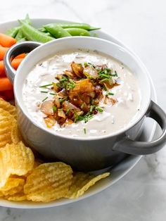 a bowl of dip surrounded by chips and carrots