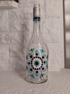 an empty glass bottle with blue and black designs painted on it sitting on a counter