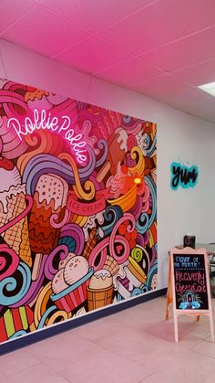 an ice cream parlor with a large mural on the wall and neon lights above it