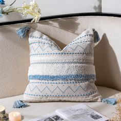 a blue and white pillow sitting on top of a couch next to a candle holder