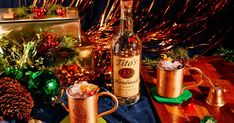 two copper mugs filled with drinks on top of a table next to christmas decorations