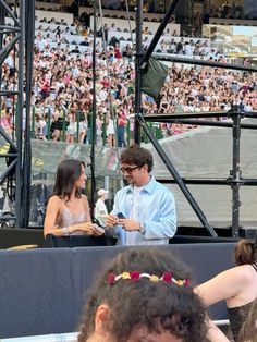 a man standing next to a woman in front of a crowd on top of a stage