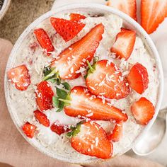 a bowl of oatmeal with strawberries and coconut flakes on top