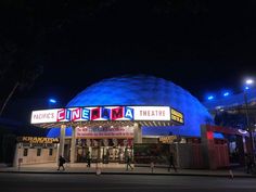 people walking in front of the entrance to an amusement park at night with lights on