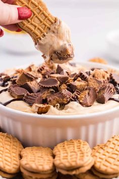 a person scooping ice cream out of a bowl filled with cookies and waffles