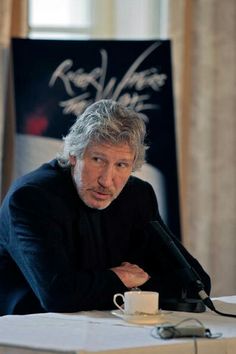 a man sitting at a table with a cup in front of him