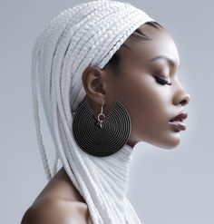 an african woman with braid hair wearing large black and white hoop earrings on her head