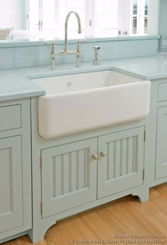 a kitchen sink sitting under a window next to a counter top with drawers and cupboards