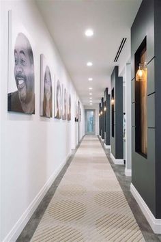 a long hallway with pictures on the wall and carpeted flooring in front of it